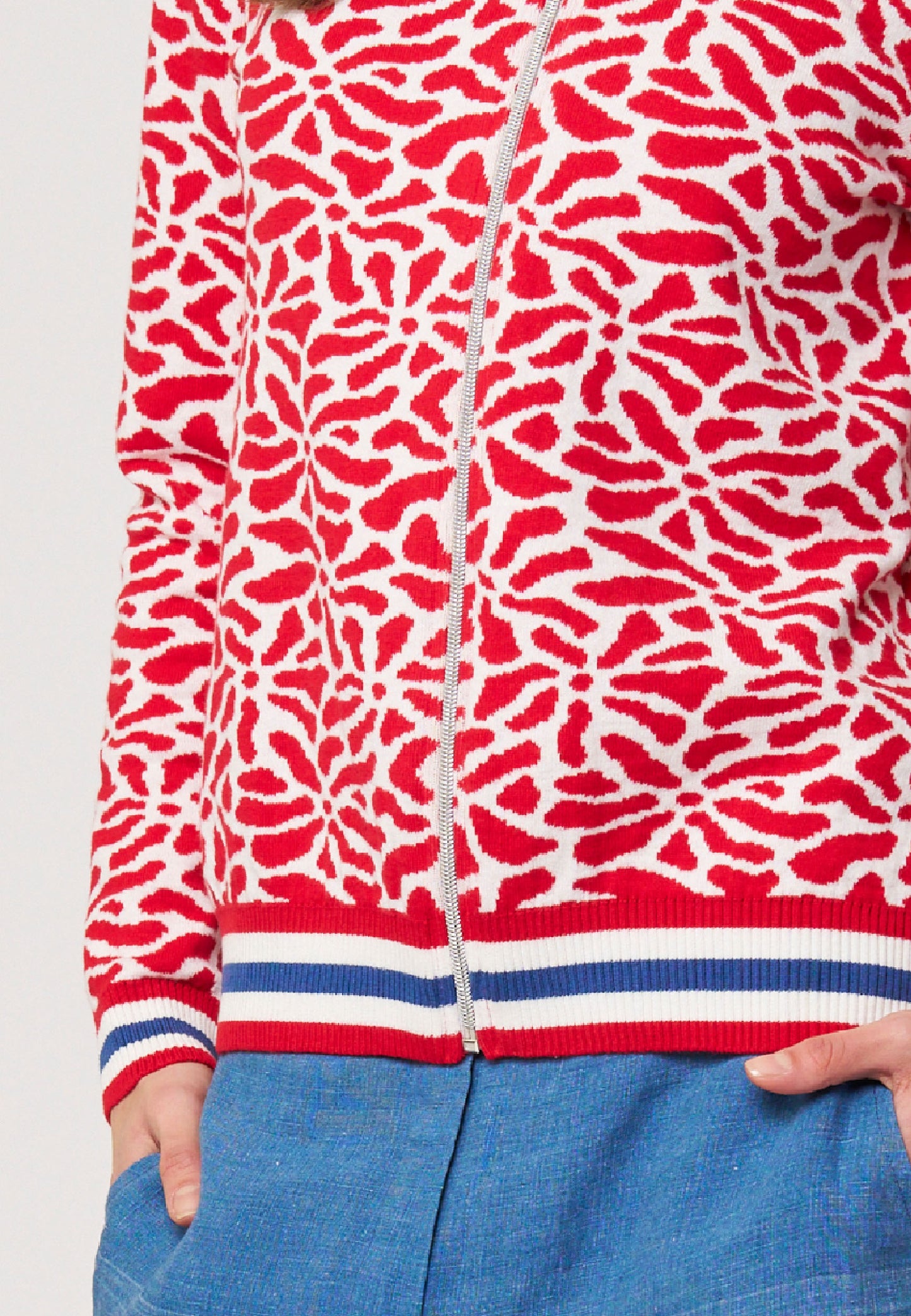 Strickjacke, Modell Alsora in Weiß-Rot mit grafischem Muster und sportlichem Bündchen am Saum, halbseitlich getragen