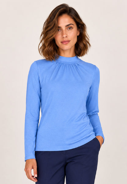 Shirt, Modell Holly in Blau mit Stehkragen und langen Ärmeln an Frau mit dunkelblauer Hose