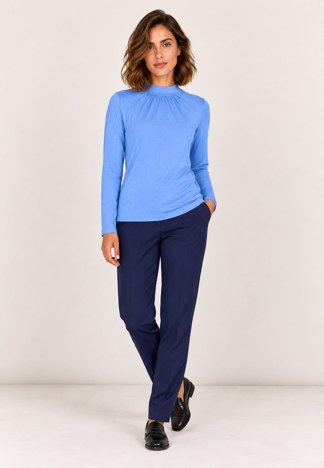 Shirt, Modell Holly in Blau mit langen Ärmeln an Frau mit dunkelblauer Hose und schwarzen Schuhen