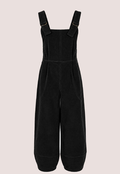 Schwarze Trägerhose, Modell Emmet, mit weitem Bein vor hellem Hintergrund